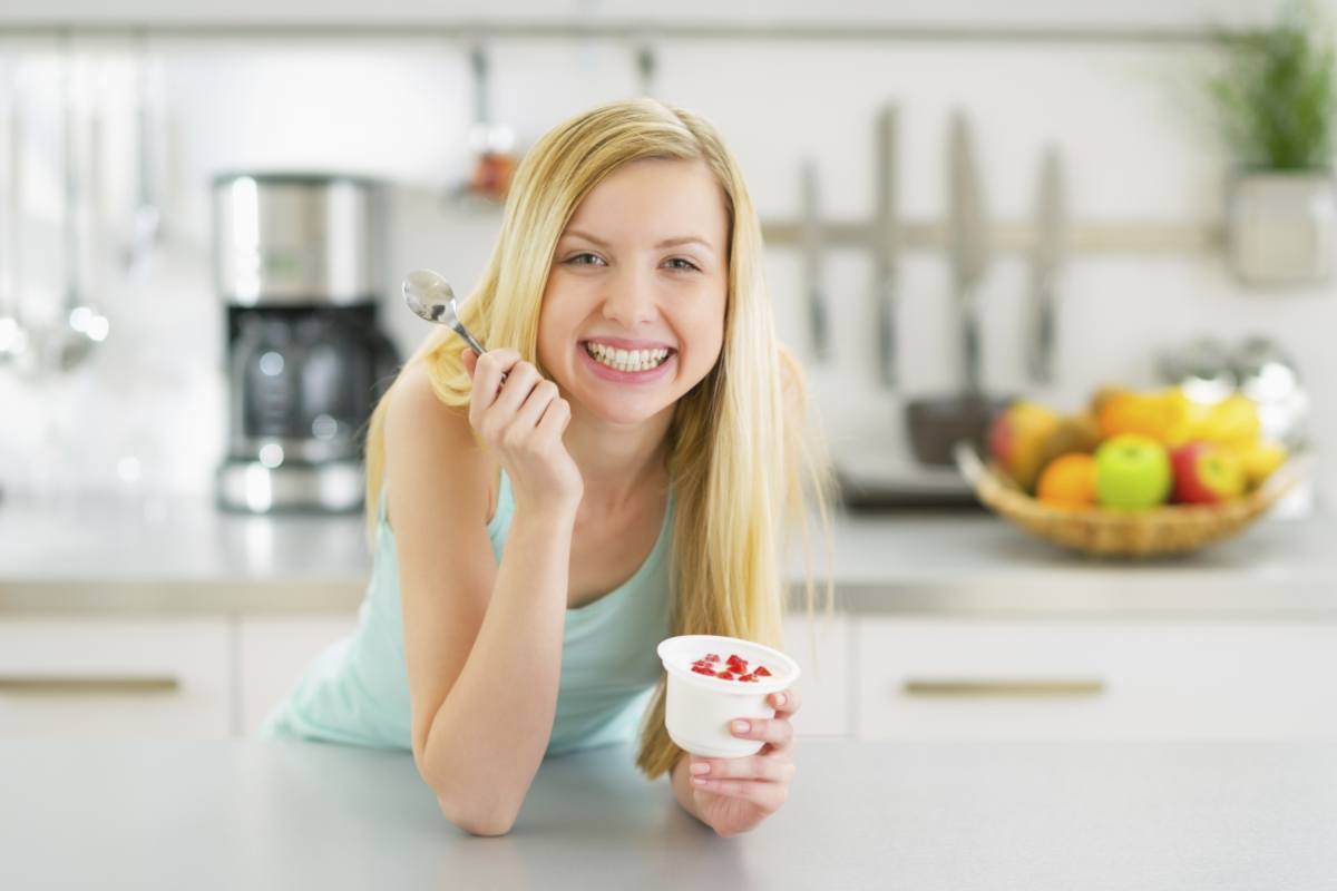 Donna sorride mangiando yogurt