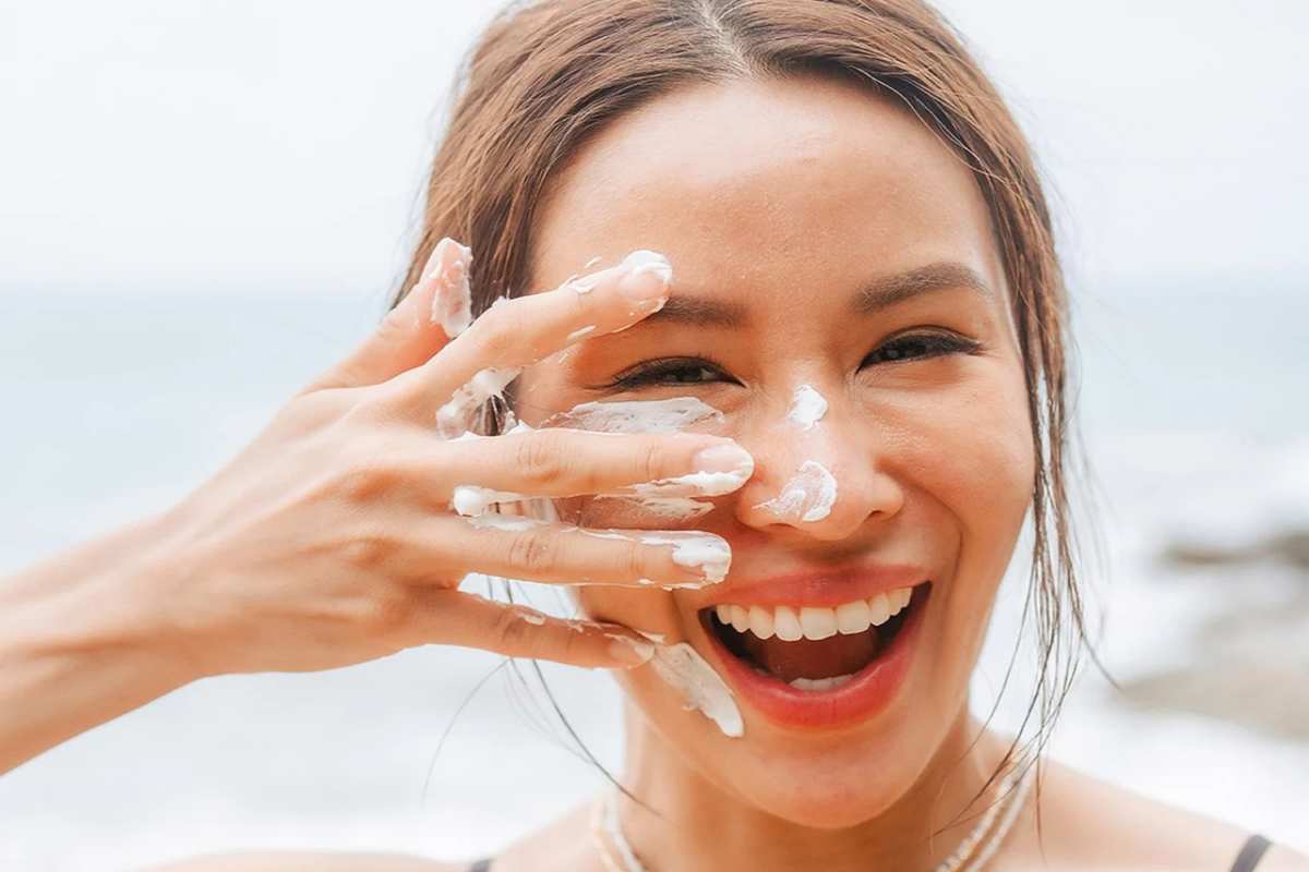 Ragazza che applica la crema solare sul viso