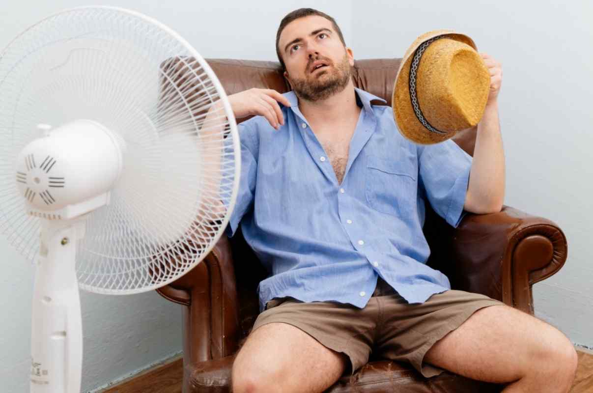 Uomo che ha caldo davanti al ventilatore