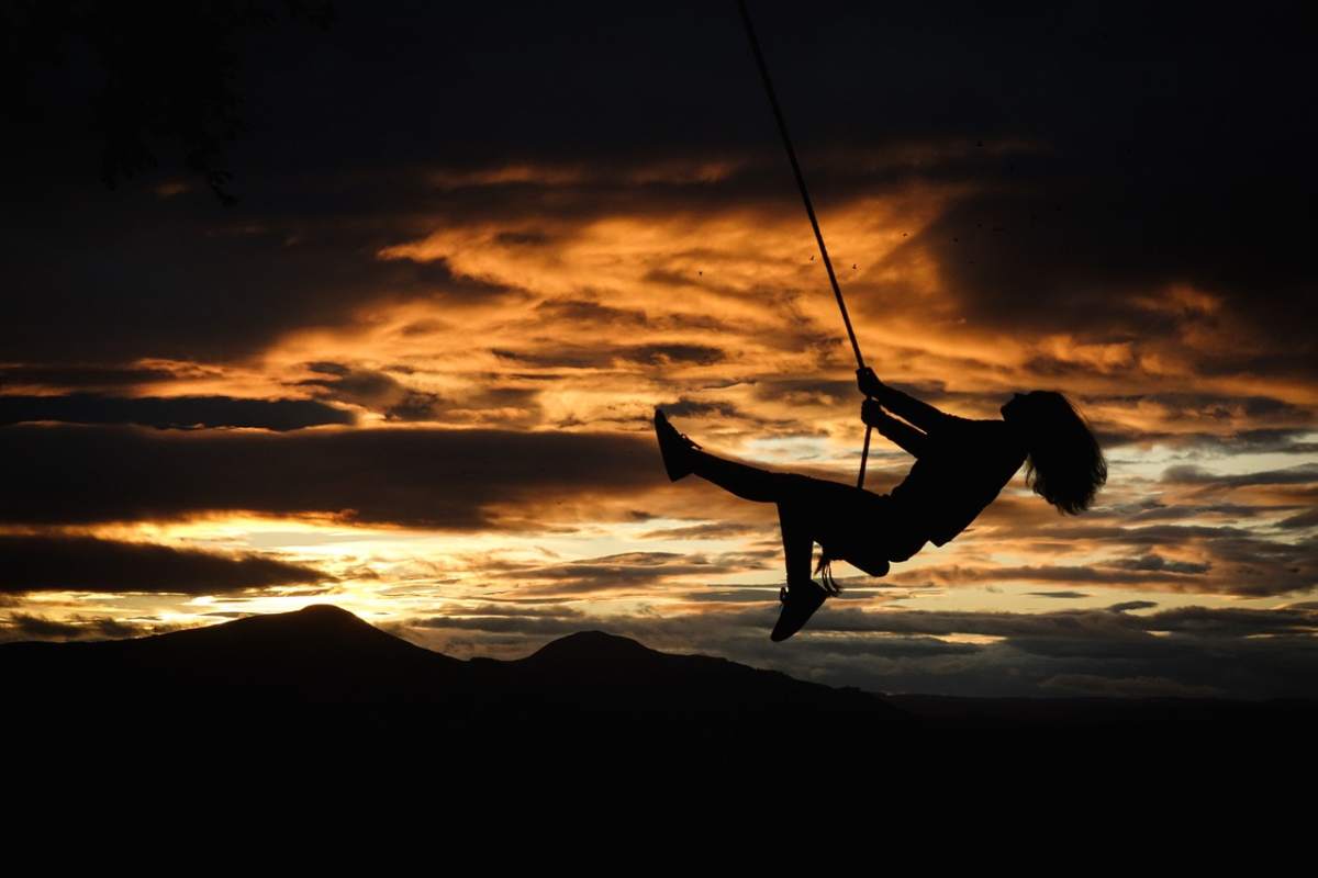 ragazza su altalena al tramonto