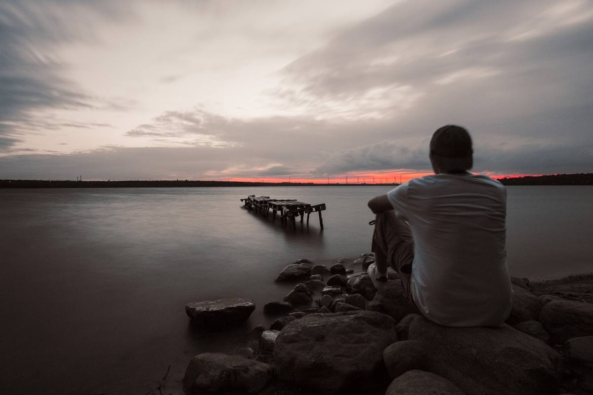 uomo solo su scogli guarda il mare