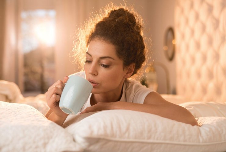 Donna beve caffè a letto