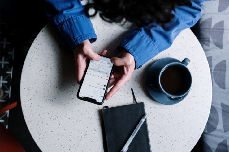 Donna con smartphone, tazza, quaderno, penna