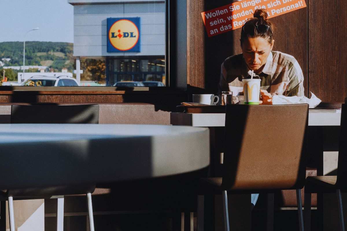 una ragazza mangia e alle spalle un lidl